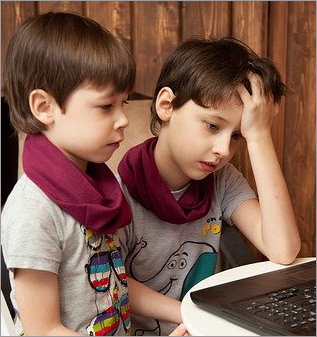 Two boys sitting together using a laptop computer